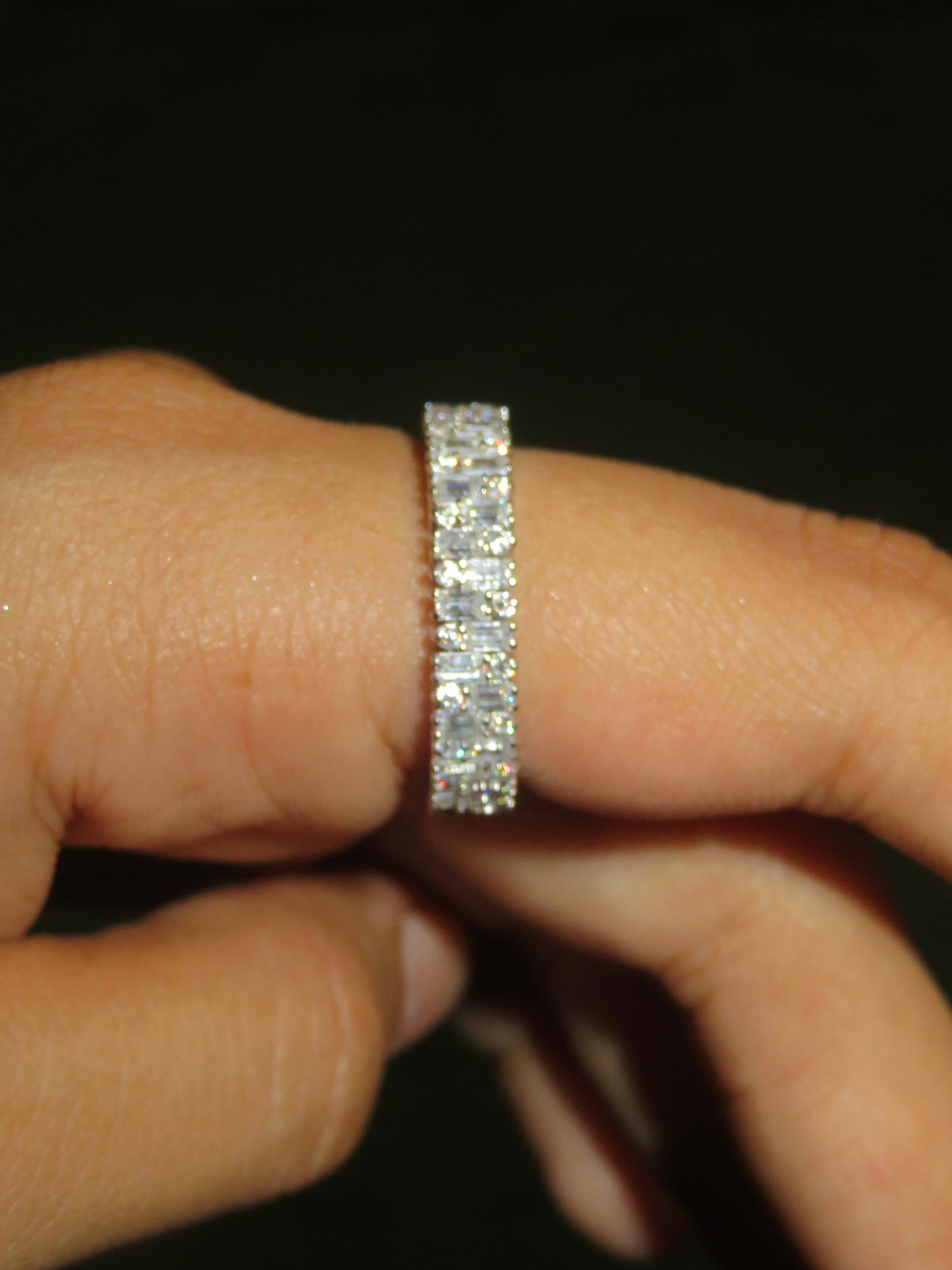 Diamond ring on a finger against a dark background