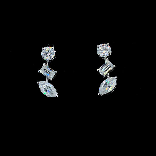 A pair of earrings featuring three moissanite stones in a sterling silver setting, with one round, one baguette, and one marquise cut.
